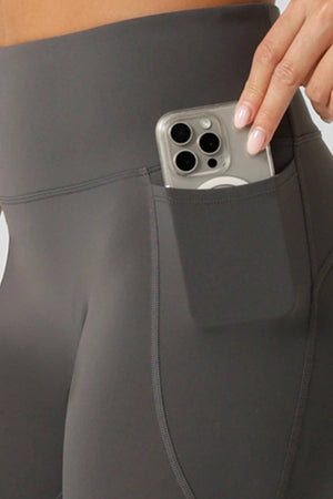 Someone, visible only from the waist down, slips a smartphone into a side pocket of Lorna Jane Amy No Ride Phone Pocket Ankle Biter Leggings featuring Active Core Stability™.