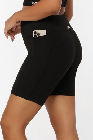 Someone models the Lorna Jane Amy Phone Pocket Tech Bike Shorts, featuring a handy side pocket for a smartphone. The image showcases the shorts’ moisture-wicking fabric from the side and back.