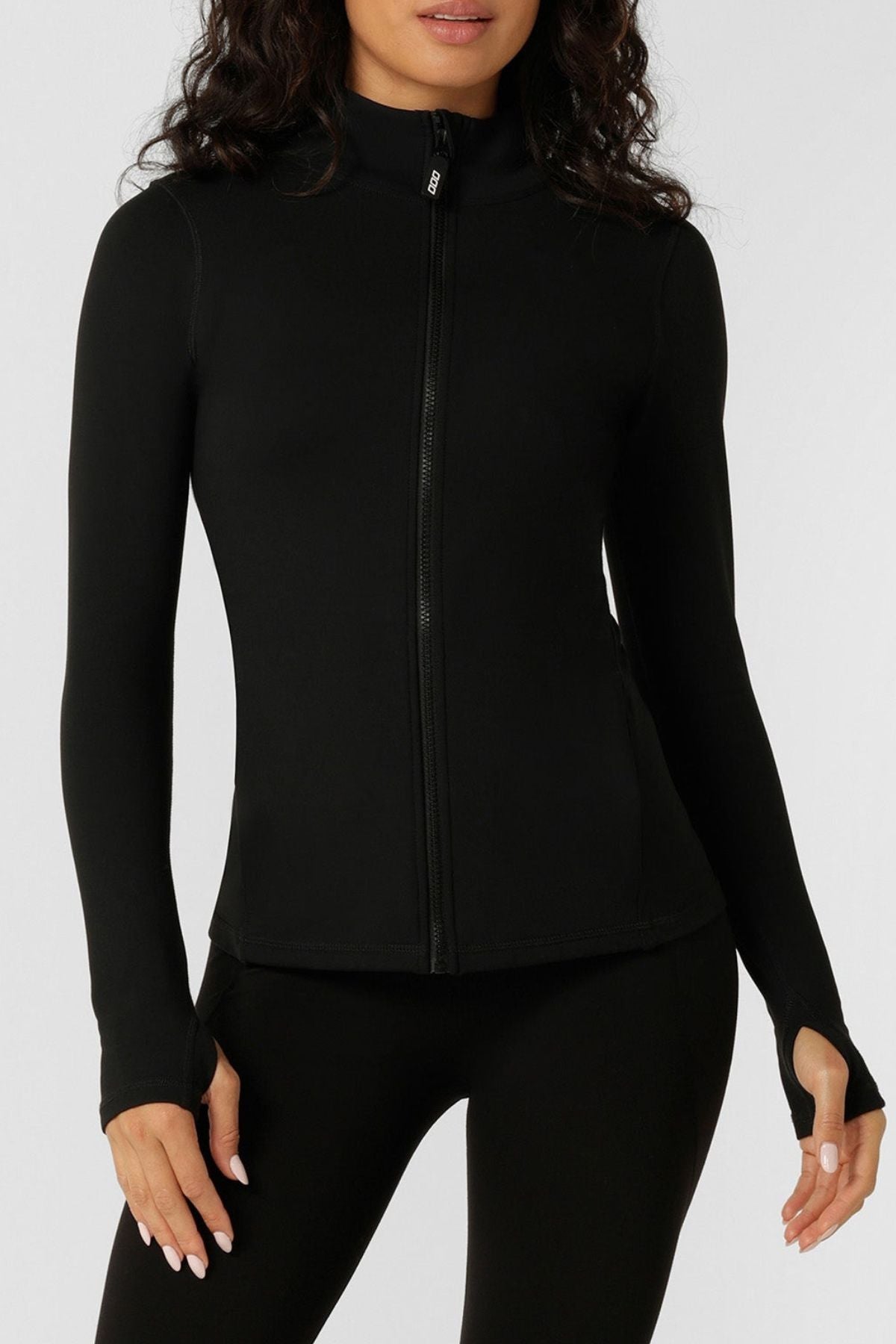 A person wearing the Lorna Jane Amy Thermal Active Zip Through Jacket in black, paired with matching black pants, stands against a plain light background.