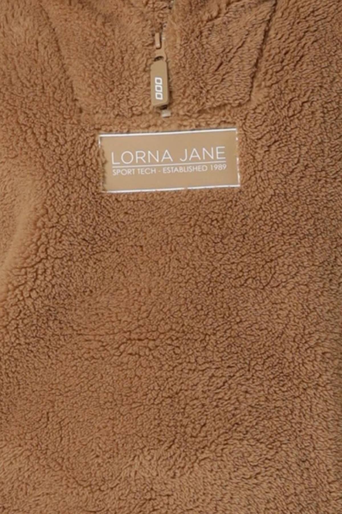 A close-up of the Lorna Jane Everyday Teddy Quarter Zip Sweat in brown, featuring a fuzzy texture, zipper detail, and "Lorna Jane Sport Tech - Established 1989" label, highlighting its comfortable oversized silhouette.