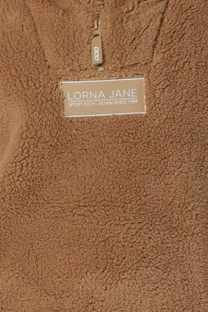 A close-up of the Lorna Jane Everyday Teddy Quarter Zip Sweat in brown, featuring a fuzzy texture, zipper detail, and "Lorna Jane Sport Tech - Established 1989" label, highlighting its comfortable oversized silhouette.