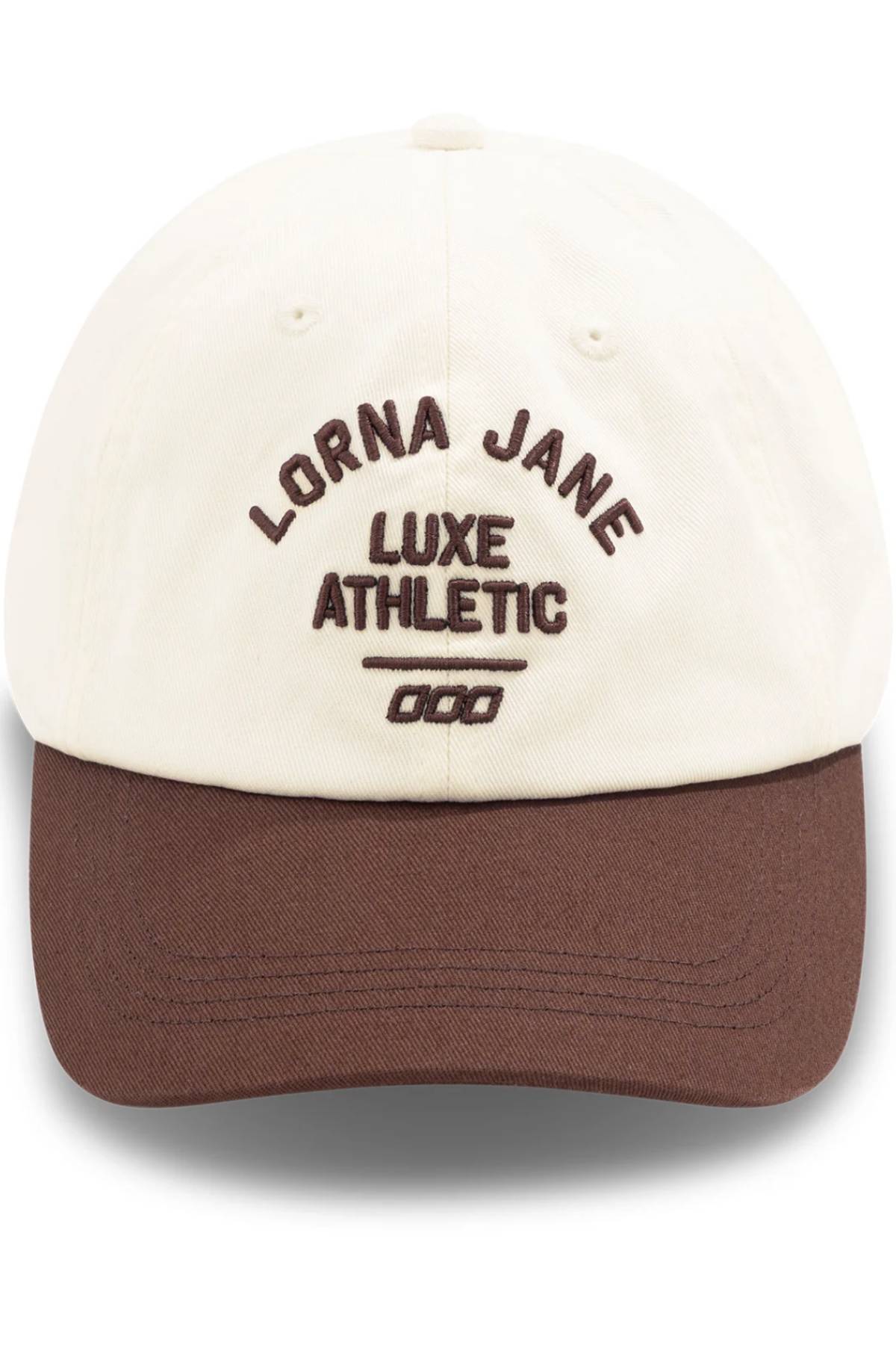 The Lorna Jane Limited Edition Lotus Heritage Cap is a 100% cotton baseball cap with a cream crown, brown brim, and "LORNA JANE LUXE ATHLETIC 000" embroidered in brown on the front. It features an adjustable band for a perfect fit.