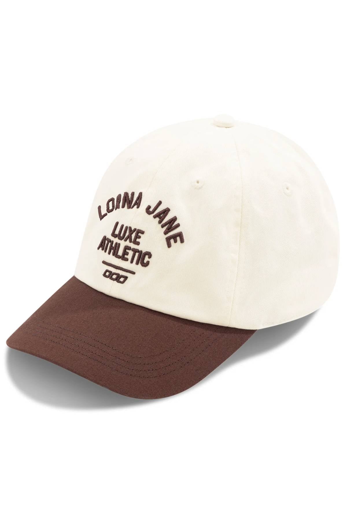 The Lorna Jane Limited Edition Lotus Heritage Cap is cream with a brown visor, features "LORNA JANE LUXE ATHLETIC" in brown embroidery on the front, is 100% cotton, and has an adjustable band for a perfect fit.