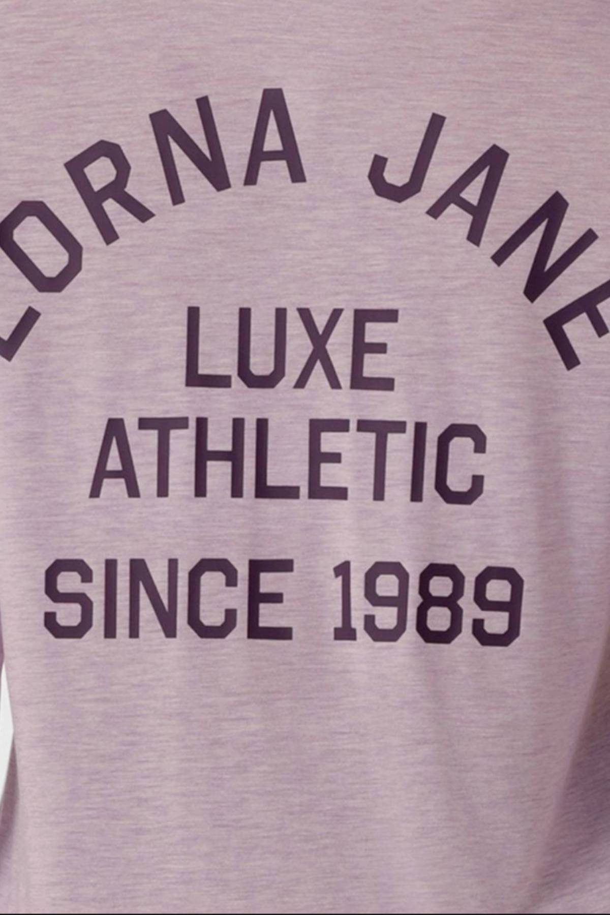 A close-up of the Lorna Jane Limited Edition Lotus Long Sleeve Top in mauve, featuring bold black text: "LORNA JANE LUXE ATHLETIC SINCE 1989." This exclusive long sleeve piece elevates your activewear collection.