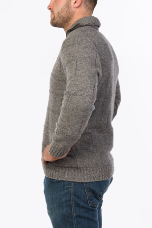 A man in the MKM Marlborough gray Merino Wool Knit sweater and blue jeans stands facing sideways against a plain white background.
