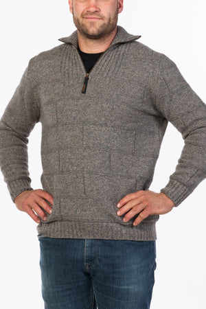 A man wearing the MKM Marlborough Merino Wool Knit zip-up sweater in gray with a textured pattern and blue jeans stands with his hands on his hips against a white background.