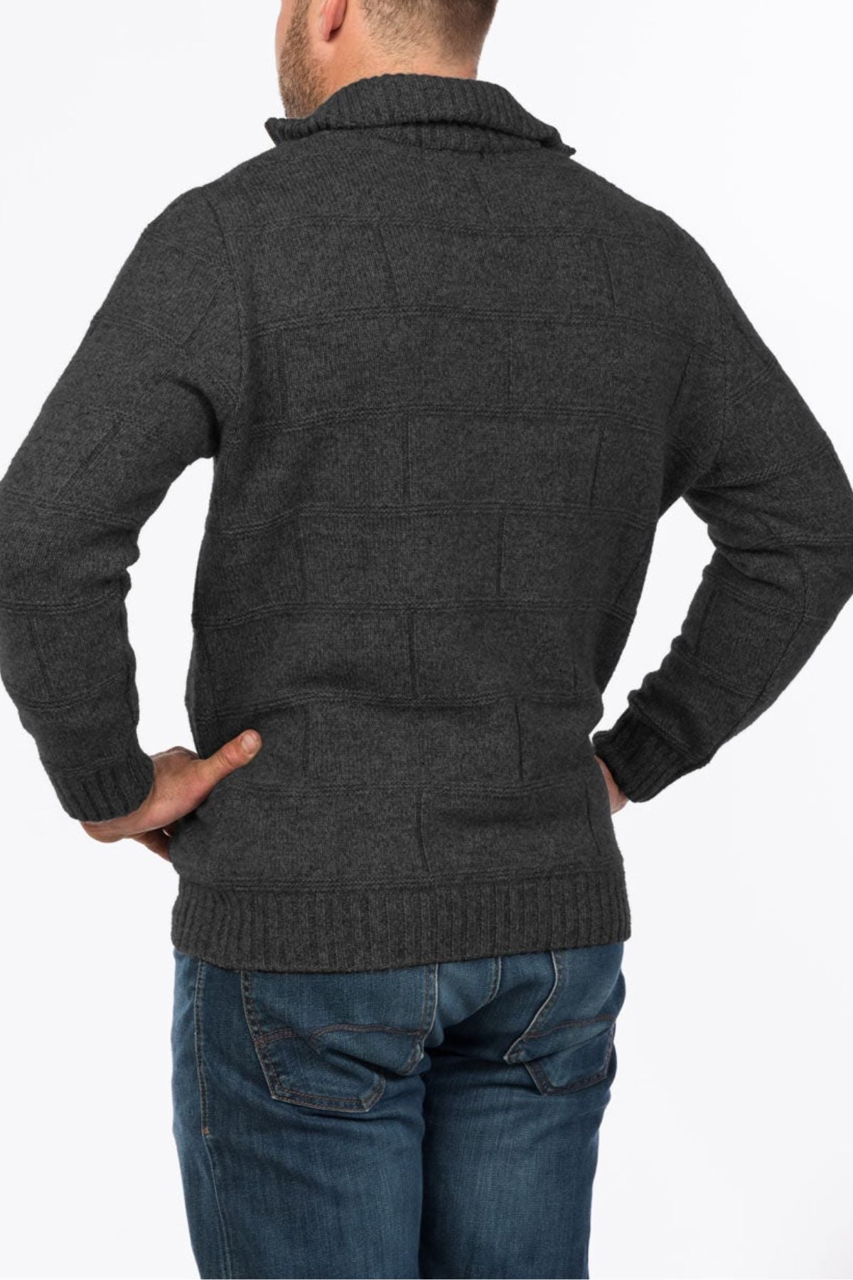 A person wearing the MKM Marlborough dark gray Merino wool knit sweater and blue jeans stands with hands on hips, facing away from the camera against a plain white background.
