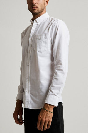 A man wearing the Mr Simple Oxford Shirt—slim-fit, white, 100% cotton with a chest pocket—and black pants stands against a plain light backdrop, facing slightly to the side.