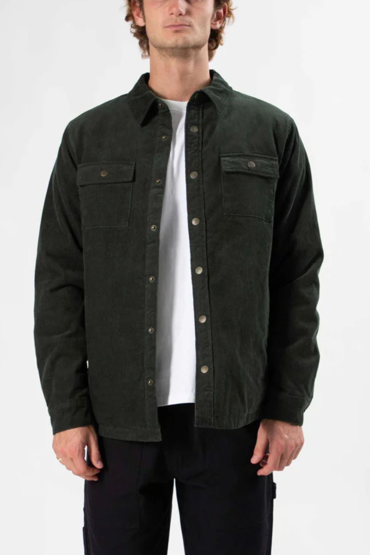 A person models the Mr Simple Quilted Cord Jacket in dark green over a white tee and black pants, highlighting classic men's outerwear against a plain light background.