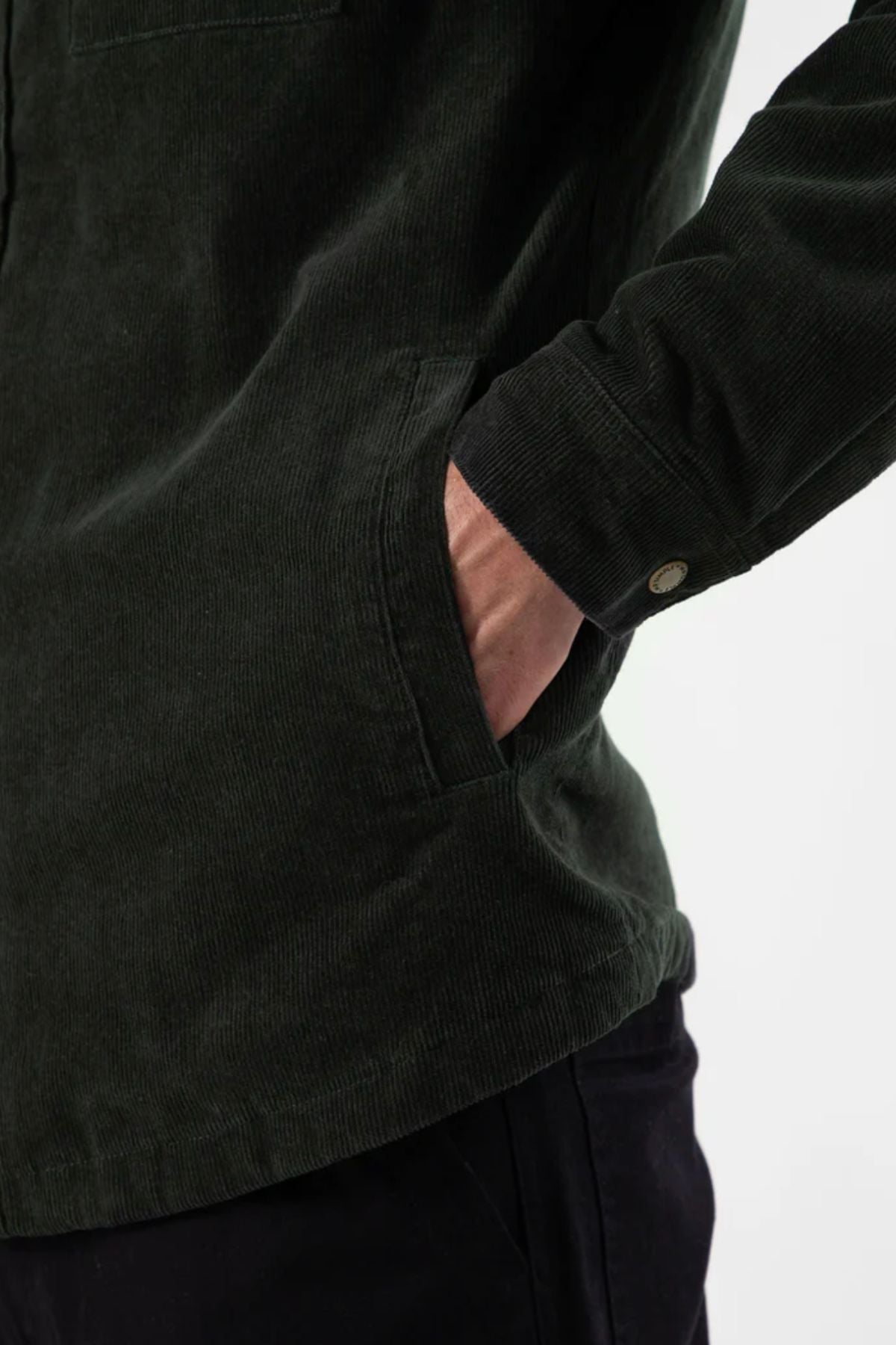 A person wears the Mr Simple Quilted Cord Jacket in dark green, their right hand in a side pocket; only the torso and part of one arm are shown against a plain background.