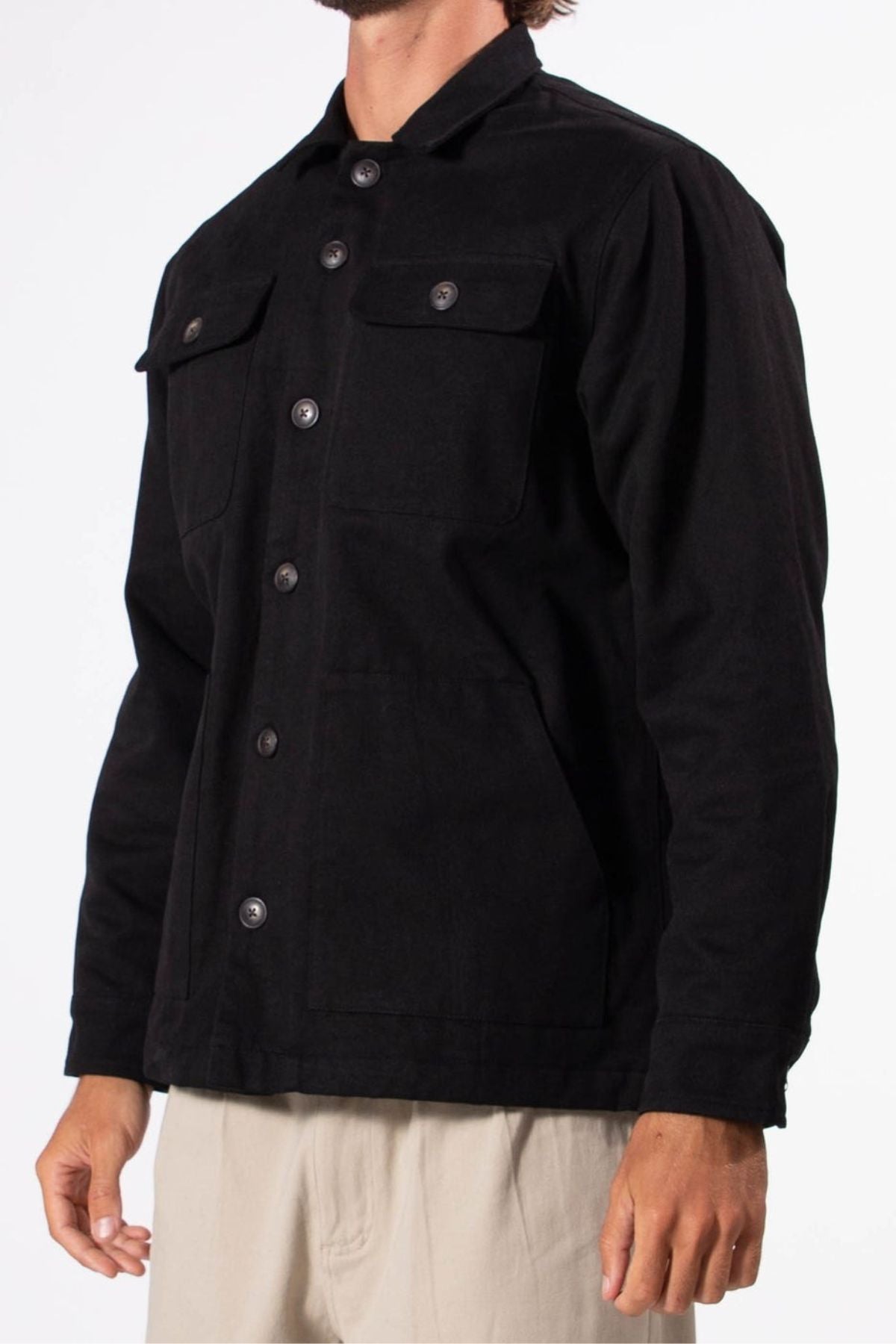 A person wears a black Mr Simple Stockyard Sherpa Jacket with chest pockets and light-colored pants, standing against a plain white background.