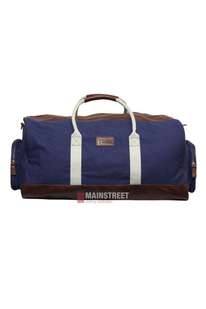 The Pilbara Long Weekender Bag, featuring blue and brown canvas with leather details, white handles, brown accents, and side pockets, is displayed on a white background. The "Mainstreet" logo is centered at the bottom.