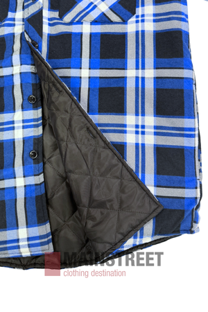 The Pilbara Flannelette Quilted Shirt in blue, black, and white plaid is shown laid flat and partially unbuttoned to reveal its black diamond-quilted inner lining. "MAINSTREET clothing destination" appears below the 100% cotton shirt.