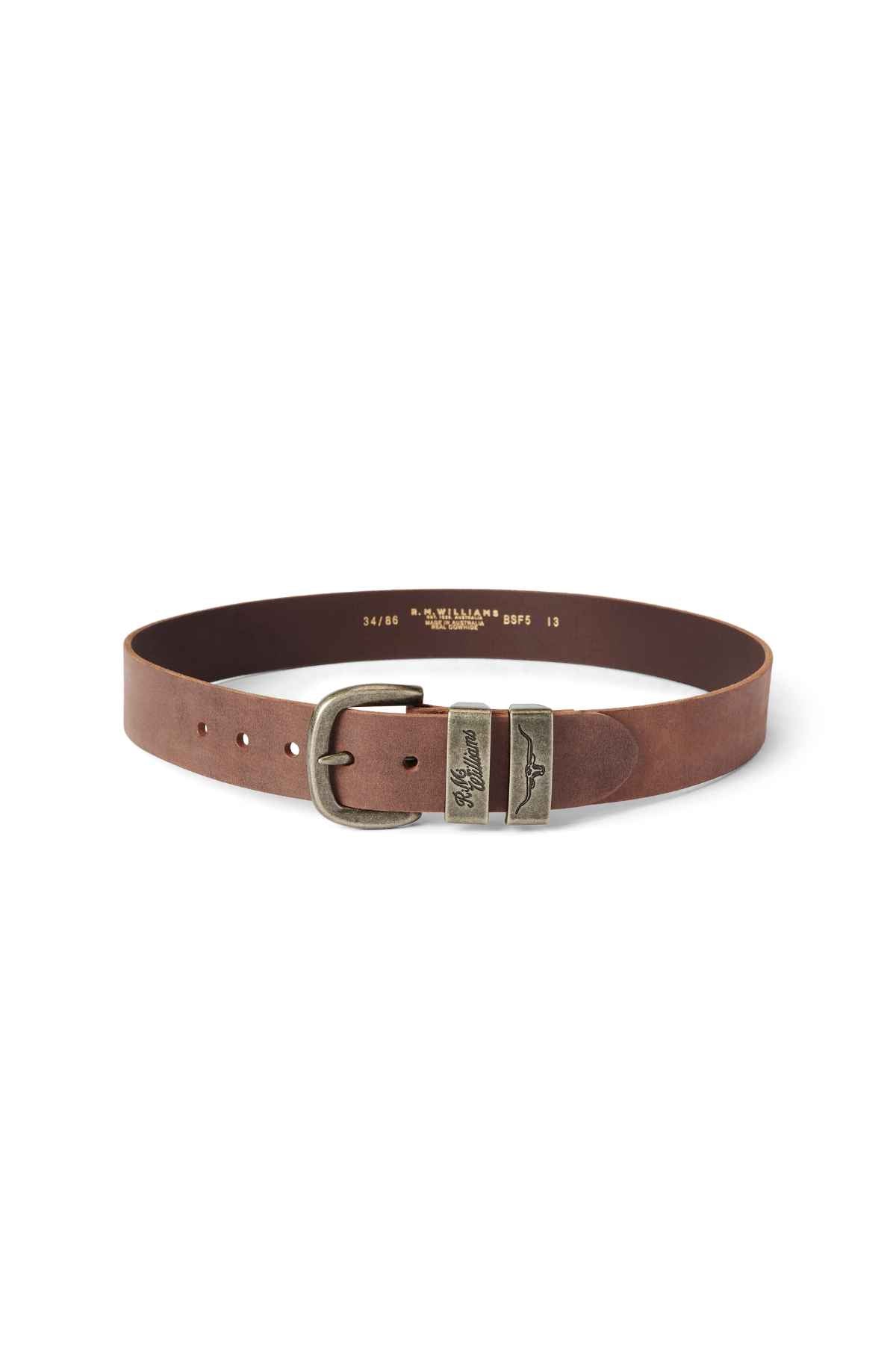 The RM Williams Drover Belt is made from rich vegetable-tanned leather with an antique brass buckle and two intricately designed metallic rings. It is circularly coiled and features several adjustment holes for a perfect fit.