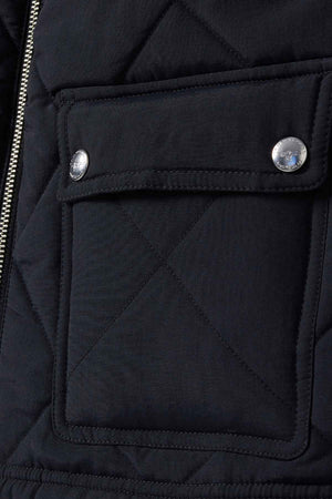 Close-up of a quilted fabric flap pocket with two silver buttons and a visible left-side zipper. The RM Williams Willippa Vest exhibits an X pattern stitch, highlighting its recycled nylon quilting.