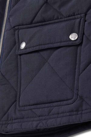 Close-up of the RM Williams Willippa Vest showing its dark quilted design with a flap pocket, two metallic snap buttons, and visible stitching details.