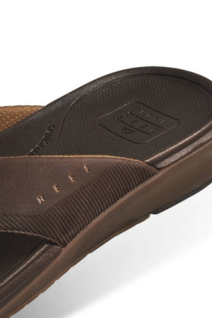 Close-up of the REEF Cushion Norte sandal, featuring water-friendly textured straps with "REEF" embossed on the side, a grippy footbed with the REEF logo, and plush EVA foam cushioning. Set against a white background.