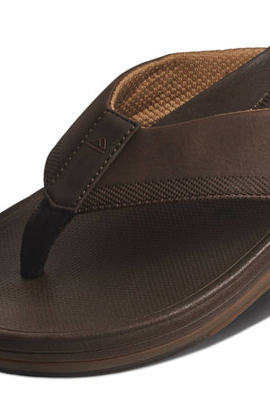 A close-up of the REEF Cushion Norte sandal, featuring brown textured straps, detailed stitching, and a cushioned water-friendly EVA foam footbed for comfort.