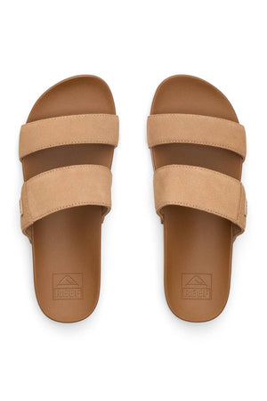 A pair of tan REEF Cushion Vista Stevie slip-on sandals with two wide suede straps and brown cushioned footbeds, viewed from above. The "REEF" logo is stamped near each heel.