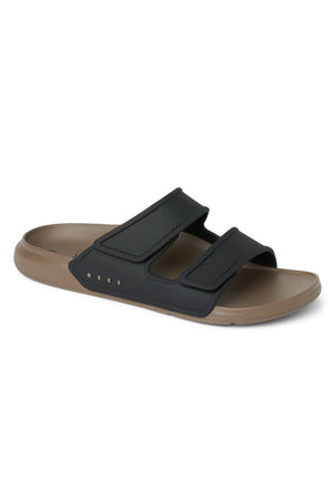 The REEF Oasis Adapt is a water-friendly slide sandal with a tan EVA footbed, black upper, and two adjustable Velcro straps. "REEF" is printed in gold on the side, combining comfort and style in one sleek design.