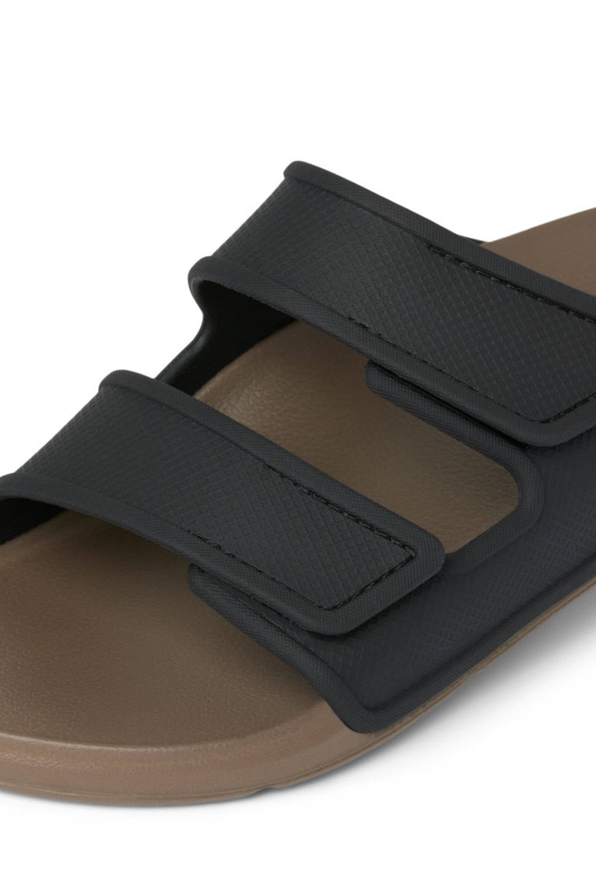 Close-up of the REEF Oasis Adapt sandal, featuring a brown EVA footbed and two wide black adjustable hook-and-loop straps. The simple, casual design makes it perfect for everyday wear.