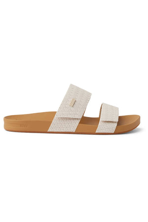 The REEF Velcro Vista Se is a tan and beige slide sandal featuring two textured straps, a flat sole, and a minimalist design—perfect for those seeking stylish and eco-friendly footwear.