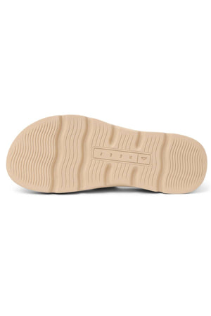 A beige rubber sole with wavy textured grooves for traction, designed for the REEF Vista Luxe Thea sandals, features a central rectangular embossed section with small symbols and raised lines for detail.