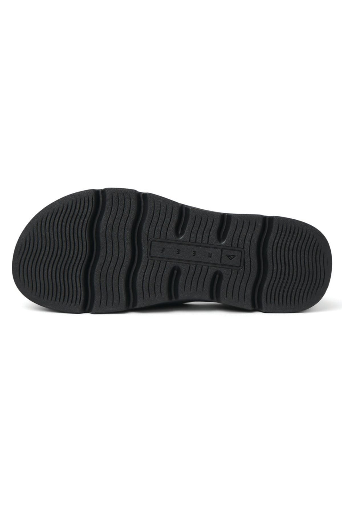 The image shows the black rubber outsole of the REEF Vista Luxe Vivianahh, featuring a wavy tread for grip and a central rectangular section with small raised letters—ideal for these vegan leather sandals with ergonomic design and cushioned footbed.