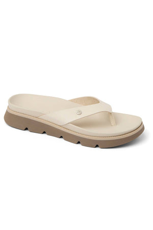 The REEF Vista Luxe Vivianahh is a beige vegan leather flip-flop sandal with a cushioned footbed, thick textured tan sole, and simple thong strap. Displayed on a white background.