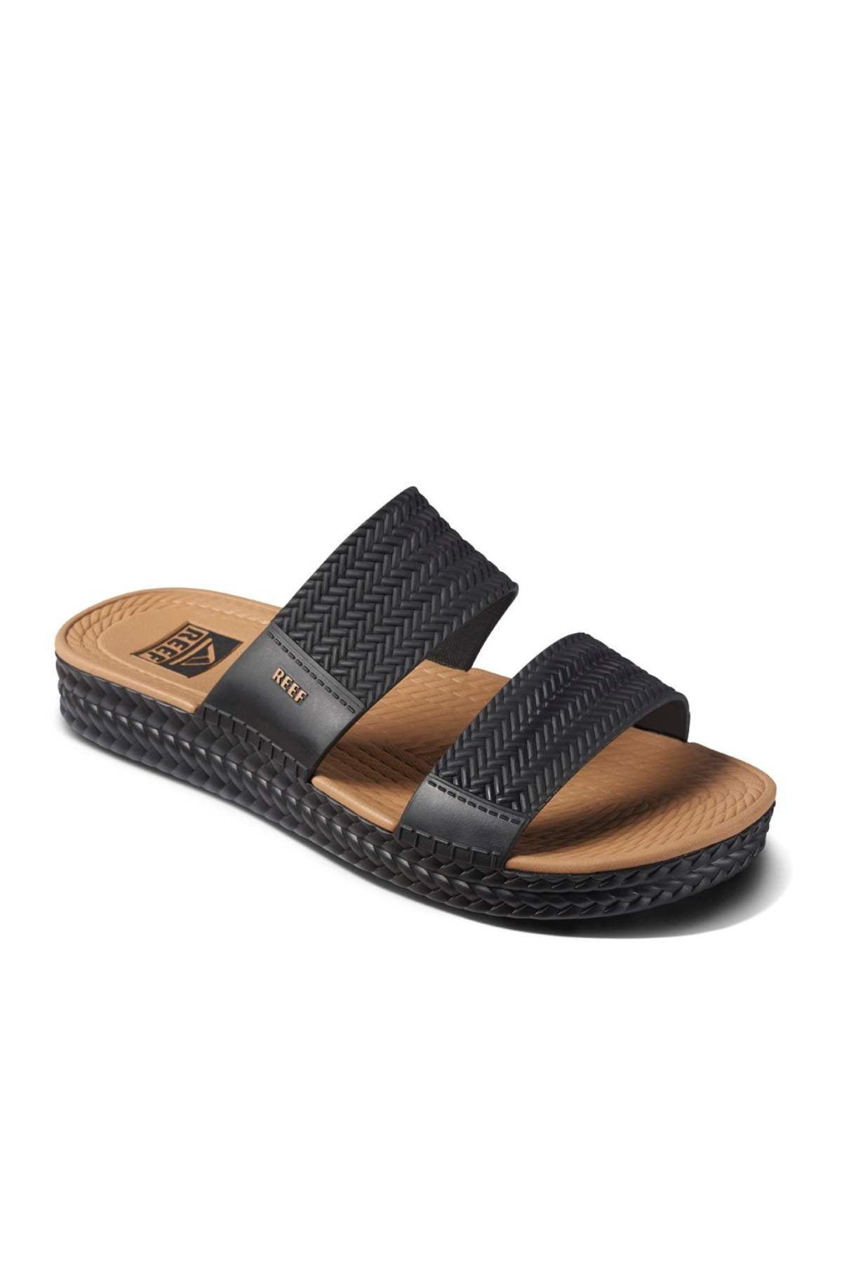 The REEF Water Vista Slide is a black sandal featuring two textured straps, a tan insole, and a woven-like design on the sole's edge. It has a flat base with dual density EVA footbed for added comfort, ideal for casual wear.