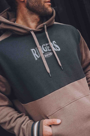 A man wears the Ringers Western Barrow Creek Pullover Hoodie, featuring "RANGERS WESTERN" embroidery on the front in an oversized fit, with one hand in the pocket and glancing slightly to the side.