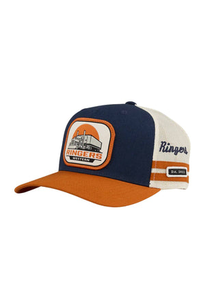 The Ringers Western Big Rig Trucker Cap is a navy blue and orange trucker hat with a cream mesh back, "Ringers Western" patch and building graphic on the front, "Kingers" embroidery on the side, "Est. 2012" label, and adjustable snapback.