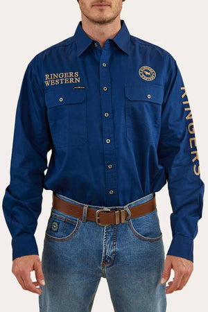 A man wears the Ringers Western Hawkeye Embroidered blue long-sleeve shirt with UPF50+ protection, "RINGERS WESTERN" text on the chest and sleeve, paired with blue jeans and a brown belt.
