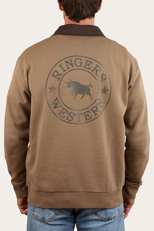 A man in blue jeans stands with his back to the camera, wearing a brown Ringers Western Lachlan 1/4 Zip Crew made from brushed fleece with the "Ringers Western" logo and a bull graphic on the back.