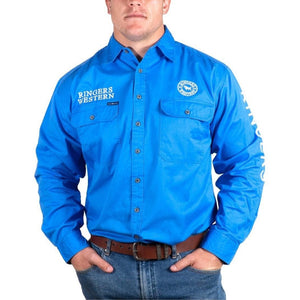 A man sports the Ringers Western Hawkeye Embroidered Shirt, a bright blue button-up with "Ringers Western" on the chest and sleeve. Made of 100% cotton, it offers UPF50+ protection and includes two chest pockets. He pairs it with blue jeans and a brown belt for a casual look.