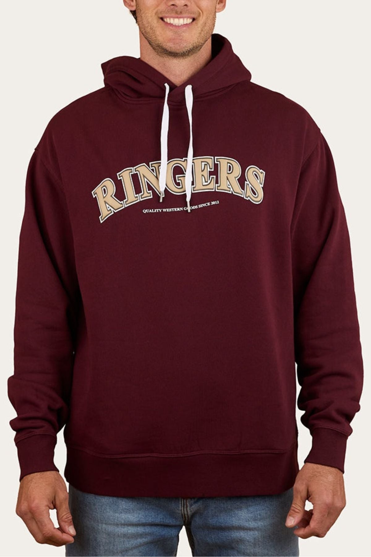 Someone wears a maroon Ringers Western Princeton Hoodie with white drawstrings, featuring bold "RINGERS" text across the chest and smaller letters below, styled in an oversized fit with blue jeans.
