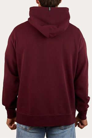 A person in a maroon Ringers Western Princeton Hoodie and blue jeans is seen from behind against a plain light background.