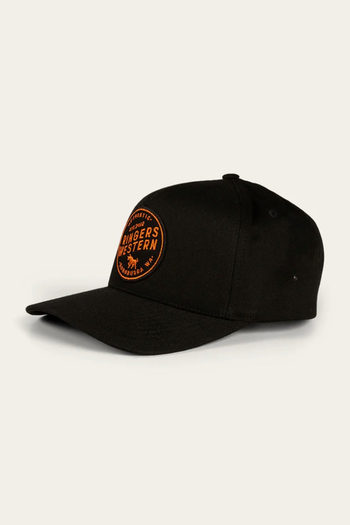 The Ringers Western Rye Baseball Cap is a stylish black cotton twill cap featuring a curved brim and an orange embroidered patch on the front. The patch prominently displays "Ringers Western" along with additional smaller text and a logo. With its six-panel design and small button on top, this cap combines both fashion and comfort.