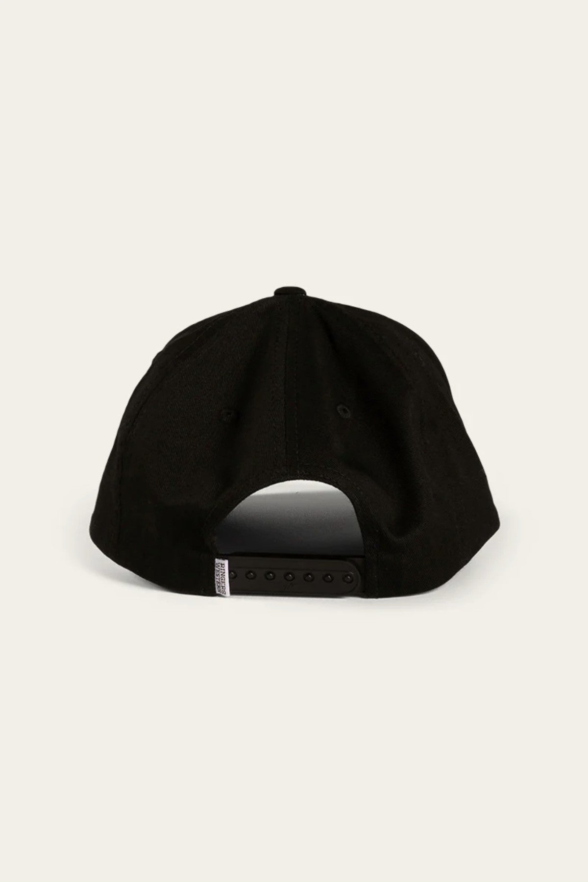 A rear view of the Ringers Western Rye Baseball Cap showcases its sleek black cotton twill design, complemented by an adjustable strap with a snapback closure. A small white rectangular tag can be seen on the left side of the strap, all set against a plain light-colored background.