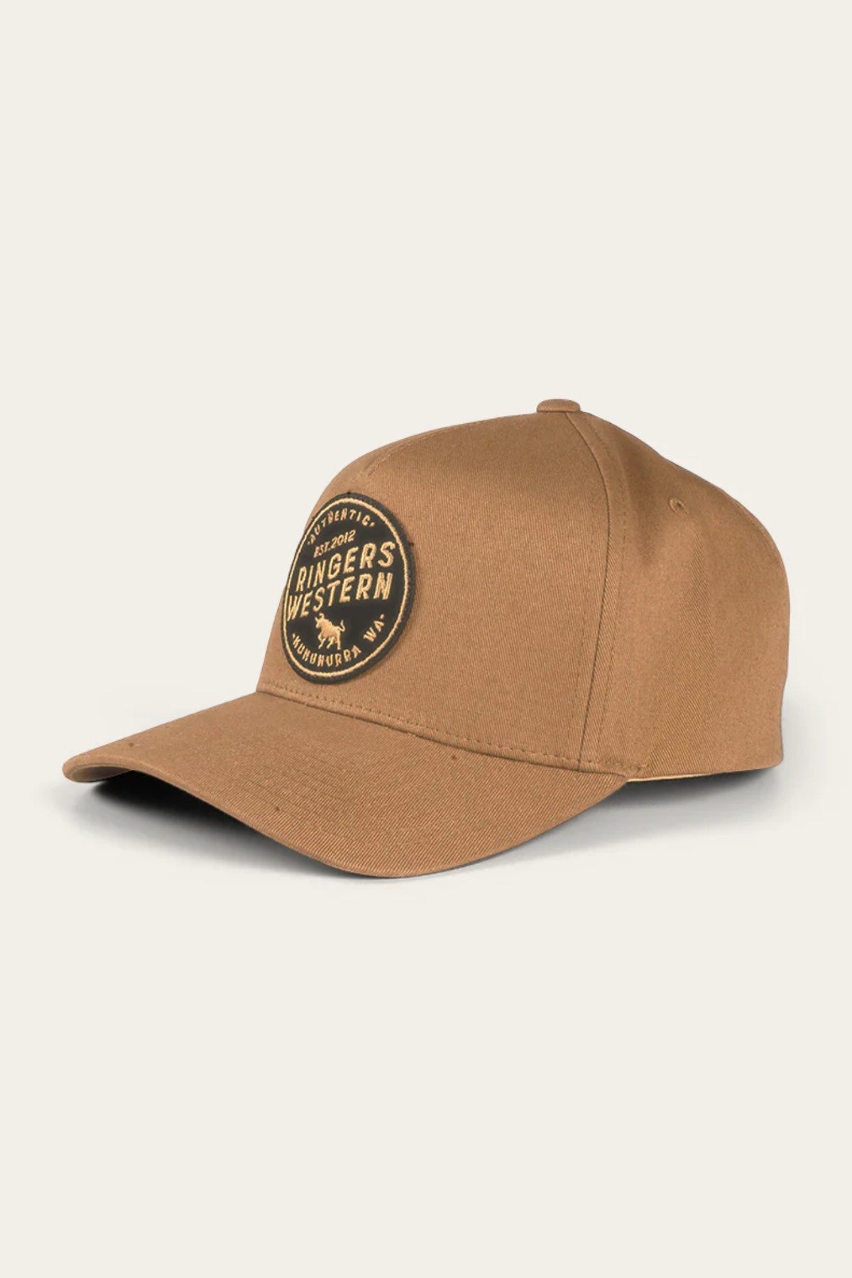 The Ringers Western Rye Baseball Cap is a brown Cotton Twill baseball cap adorned with a black circular patch on the front, displaying "Ringers Western" alongside a cow silhouette. Featuring a curved brim and structured panels, it exudes a classic, rugged look against an off-white background.