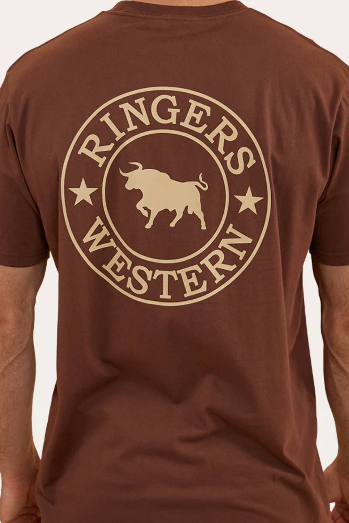 A person wearing a Ringers Western Signature Bull Loose Fit T-Shirt, made from 100% cotton jersey, featuring a large circular "RINGERS WESTERN" logo with a bull and two stars on the back.