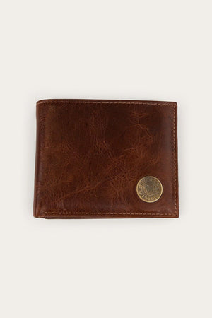 The Ringers Western Toro Biggo Wallet, crafted from brown pull-up leather with visible stitching and finished with a round brass emblem in the lower right corner, is displayed against a plain light background. This wallet combines classic style with enhanced durability for everyday use.