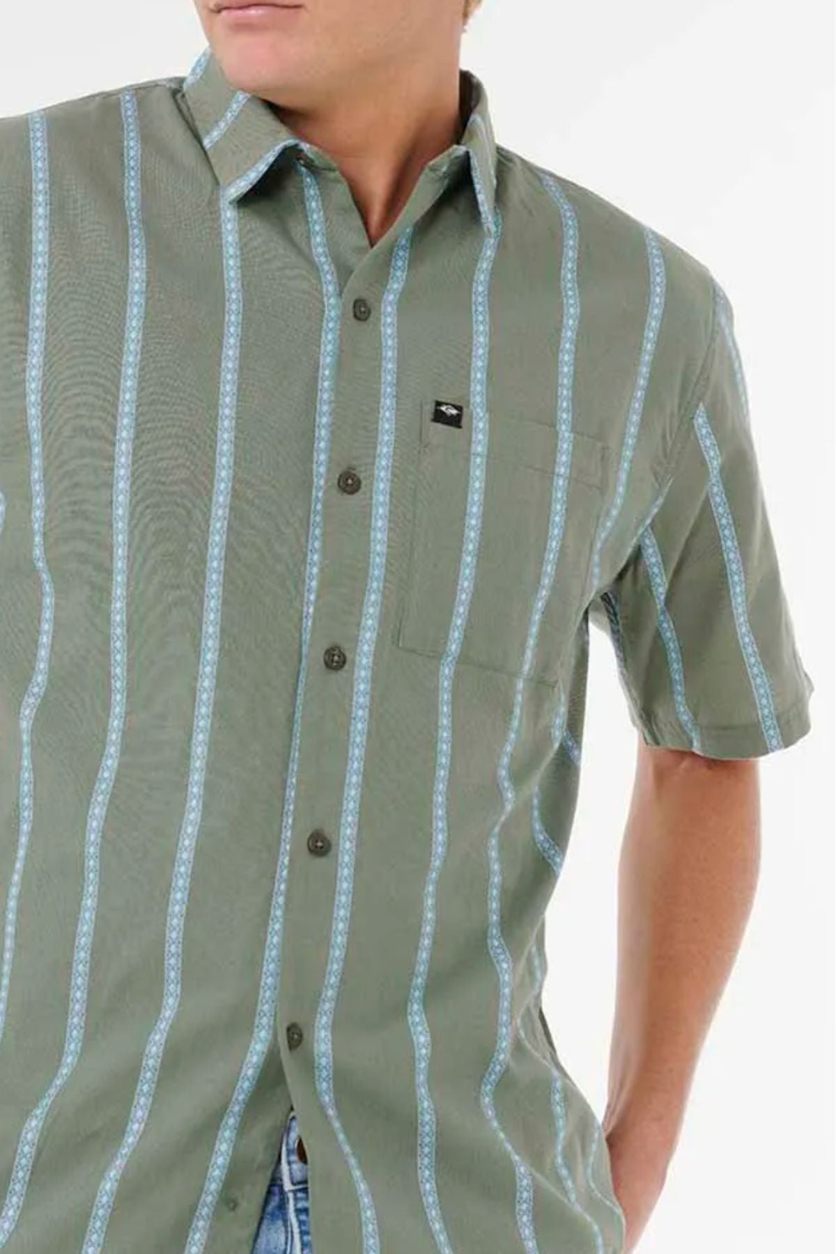 A person wears the Rip Curl Classic Surf Stripe Short Sleeve Shirt—a green, short-sleeved button-up with light blue vertical stripes and a front pocket—standing against a plain white background.