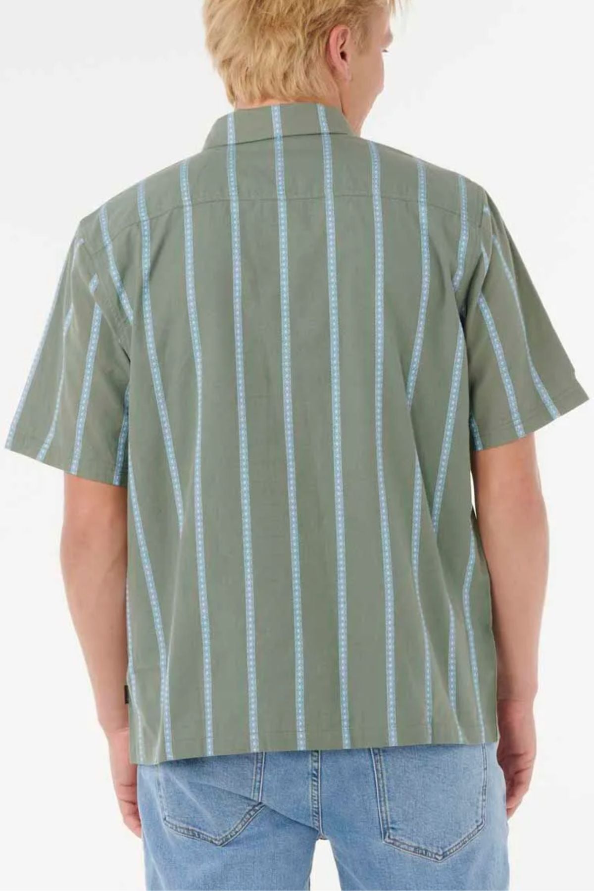 Someone with short blond hair is wearing the Rip Curl Classic Surf Stripe Short Sleeve Shirt in green with light blue vertical stripes and light blue jeans, facing away from the camera against a white backdrop.