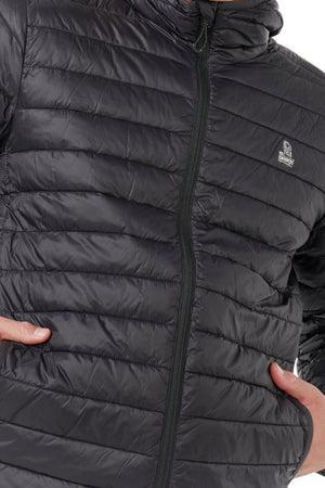 A person wearing the Rip Curl Anti Series Search Puffer Hood, a black, quilted, water-repellent jacket with hands in side pockets and a small white logo on the left chest.