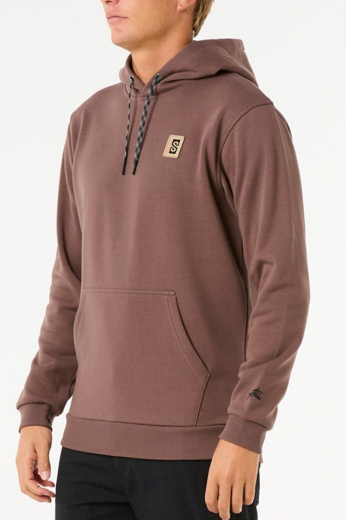A person wears the Rip Curl Anti Series Search Base Hood, a brown bonded polar fleece hoodie with black drawstrings, front pocket, small "S" chest patch, and sleeve logo, shown against a plain white background.