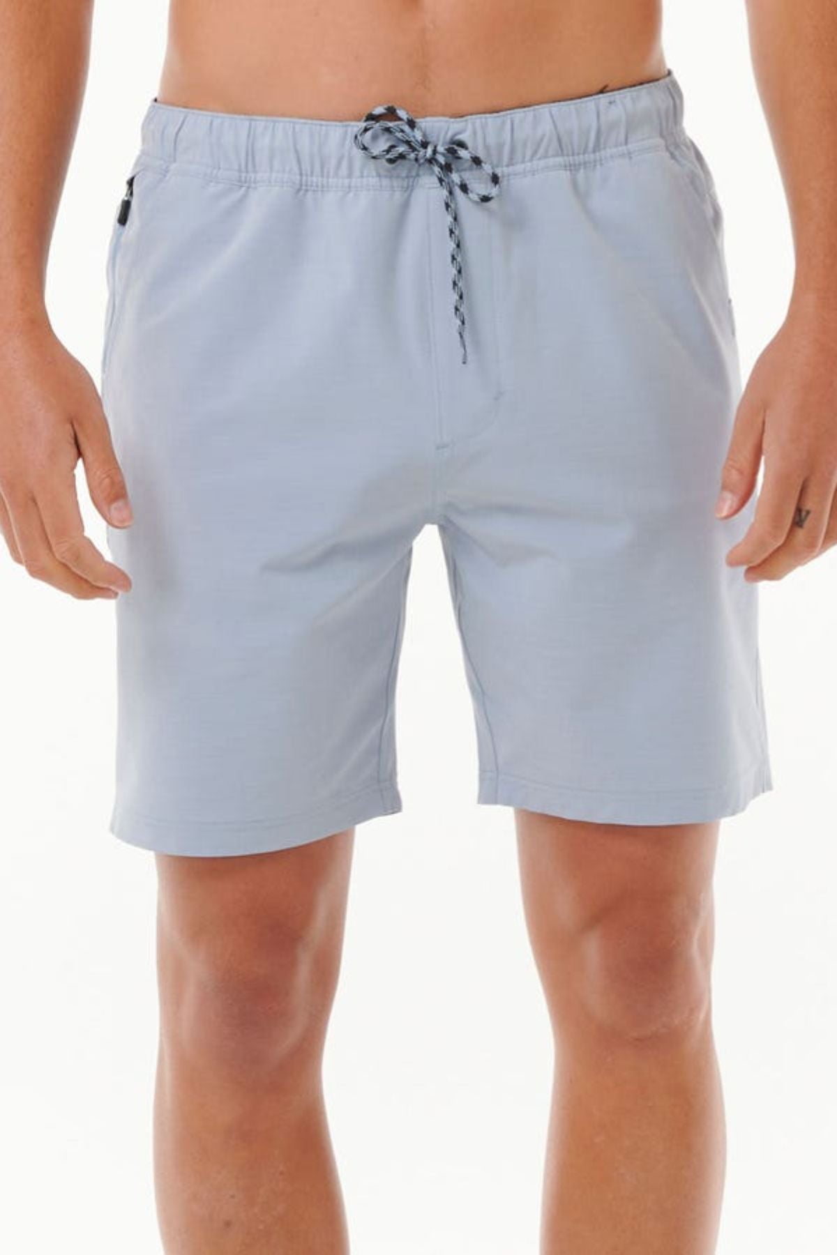A person wearing Rip Curl Boardwalk Jackson Volley shorts in light gray, featuring a black-and-white drawstring, stands against a plain background. These knee-length shorts offer a relaxed fit and quick-dry fabric, combining style with functionality.