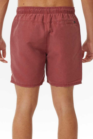 Back view of a person wearing Rip Curl Bondi Volley swim shorts crafted from recycled PET. These faded red shorts have an elastic waistband and a right-side small back pocket with a button, set against a plain white background.