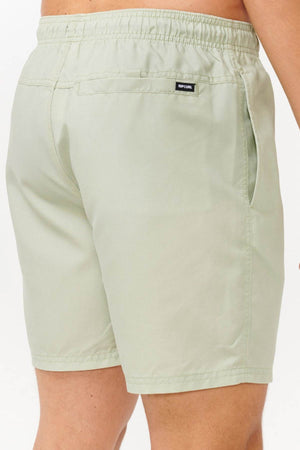 A person is wearing light green Rip Curl Bondi Volley swim trunks with an elastic waistband. Made from recycled PET, these shorts come with a back pocket decorated with a small black label and functional side pockets. Only the lower back and legs are visible against a plain white background.