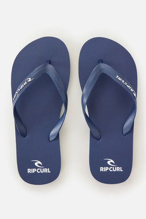 A pair of Rip Curl Brand Logo Bloom Thongs in blue, made with eco-friendly algae-blended foam and white brand logos on the heel and strap, displayed side by side on a plain white background.